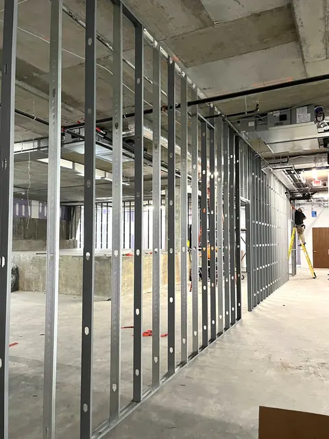 Metal stud walls standing on an open office floor, ceiling still exposed.