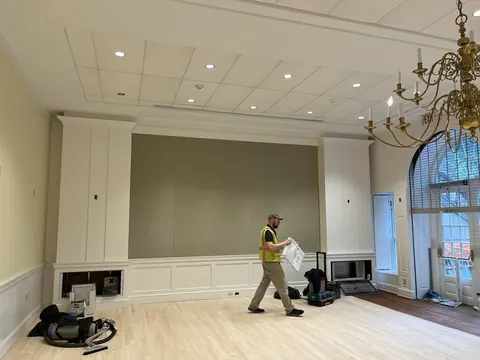 A worker crossing the ballroom in front of built-in cabinets.